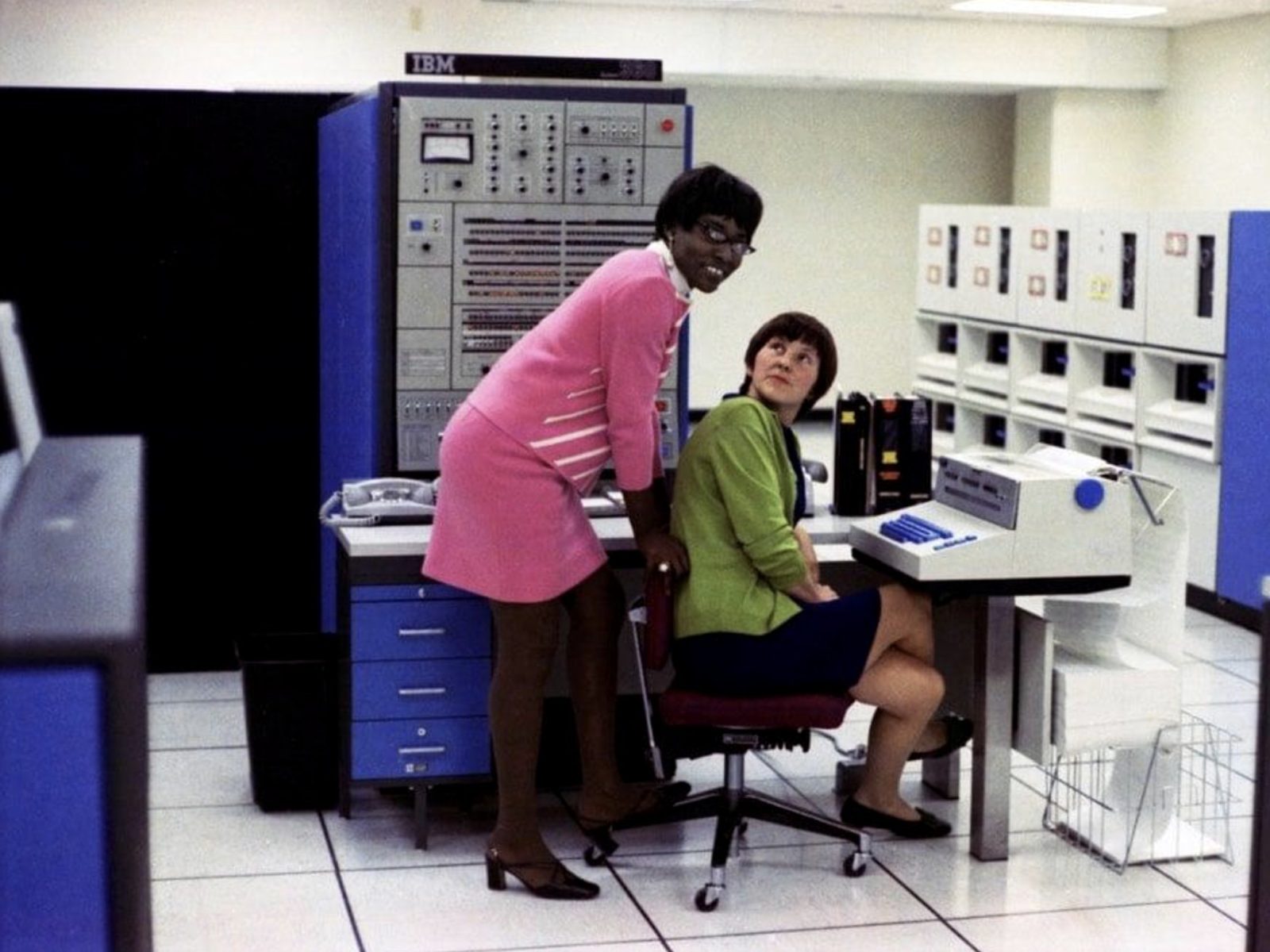 two women in a computer room beside an ibm mainframe console, 1970s