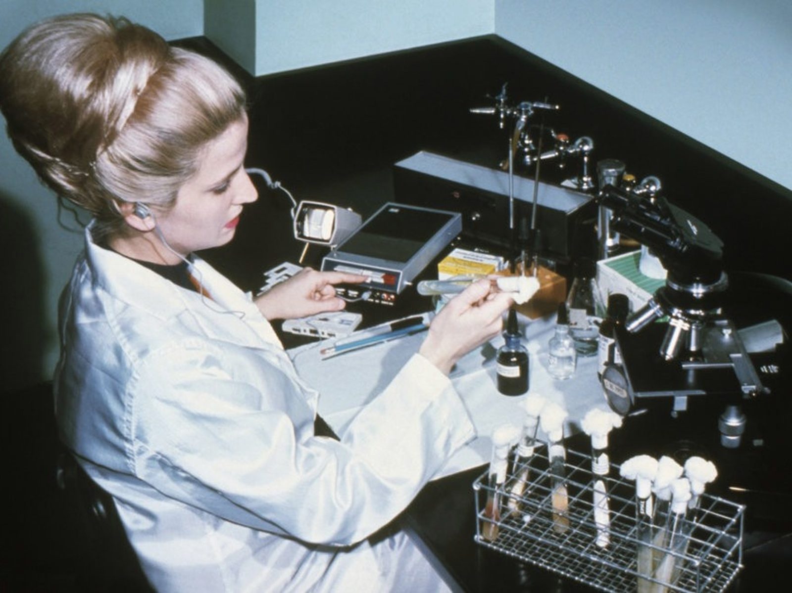 a scientist in a white lab coat preparing a sample at a laboratory bench